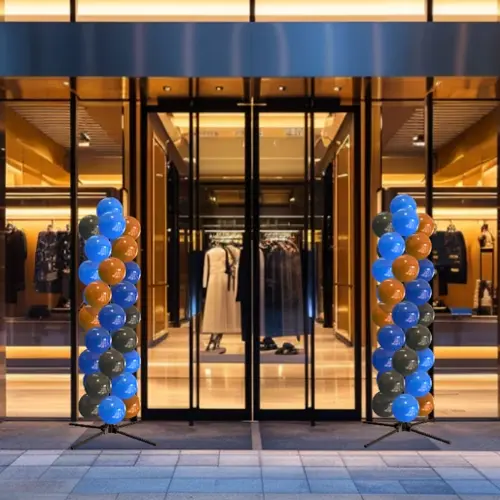 Two of the same balloon columns beside the lit entrance of a fashion store